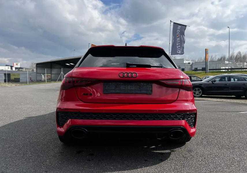 Vue arrière d'une Audi RS3 Sportback rouge 2022 avec feux LED et double sortie d'échappement noire.