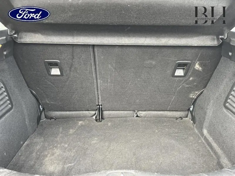 Coffre ouvert d'une Citroën C3 bleu encre 2014, montrant la banquette arrière rabattable et le tapis de coffre noir.