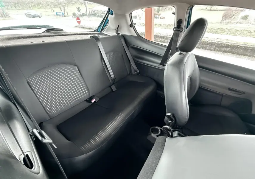 Vue intérieure arrière droite montrant les sièges noirs en tissu et cuir d’une Peugeot 206+ bleue 3 portes.