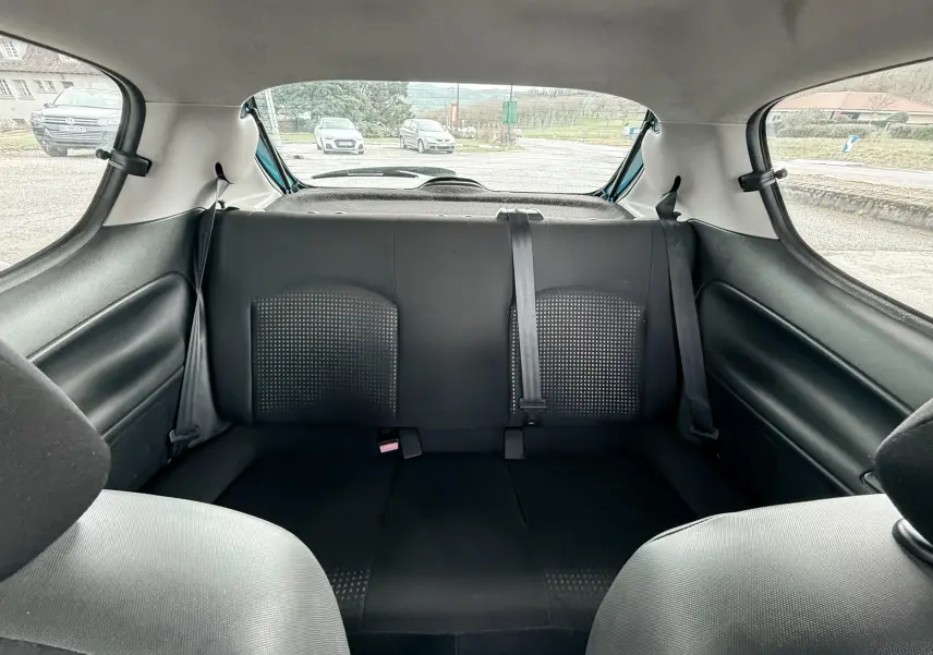 Vue intérieure arrière sur les sièges noirs en tissu de la Peugeot 206+ 3 portes, avec ceinture de sécurité centrale visible.