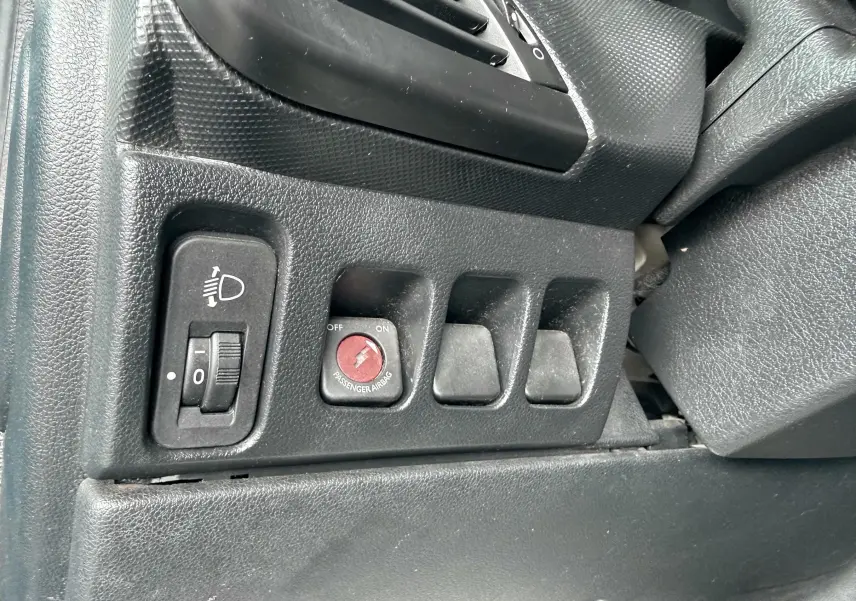 Gros plan sur les commandes noires du tableau de bord côté gauche de la Peugeot 206+ 1.1 i 60 de 2011.