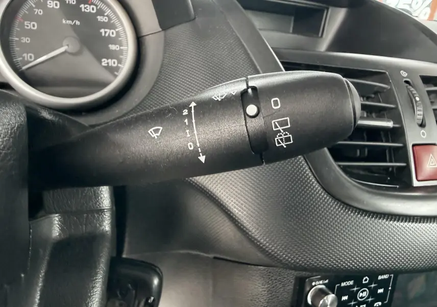 Gros plan sur la commande d’essuie-glace côté gauche du tableau de bord noir d’une Peugeot 206+ bleue.
