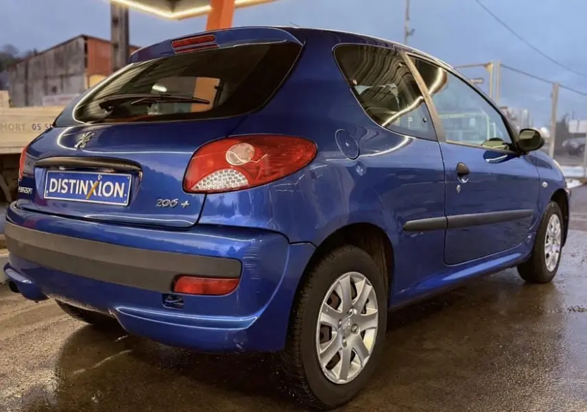 Vue 3/4 arrière droite d'une Peugeot 206+ bleue 3 portes, avec feux arrière rouges et jantes argentées.