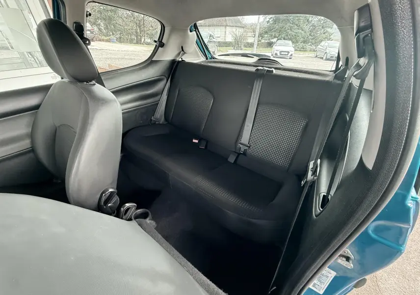 Vue intérieure arrière côté droit d'une Peugeot 206+ bleue, montrant les sièges arrière en tissu noir.