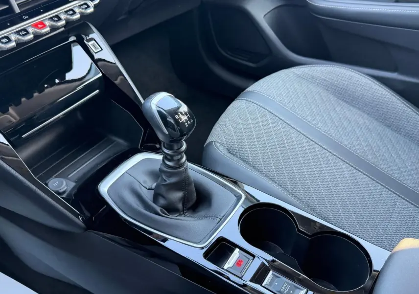 Vue rapprochée de la console centrale de la Peugeot 208 gris Artense, avec levier de vitesse manuel et siège tissu gris.