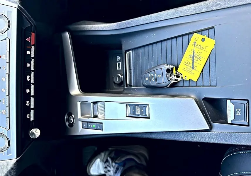 Vue plongeante sur la console centrale grise de la Peugeot 308 2025 avec clé et bouton Drive Mode visible.