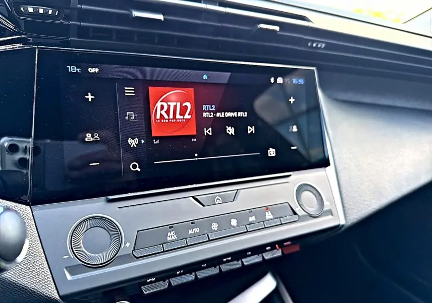 Vue rapprochée de l'écran tactile central et de la console de la Peugeot 308 gris selenium, affichant la radio RTL2.