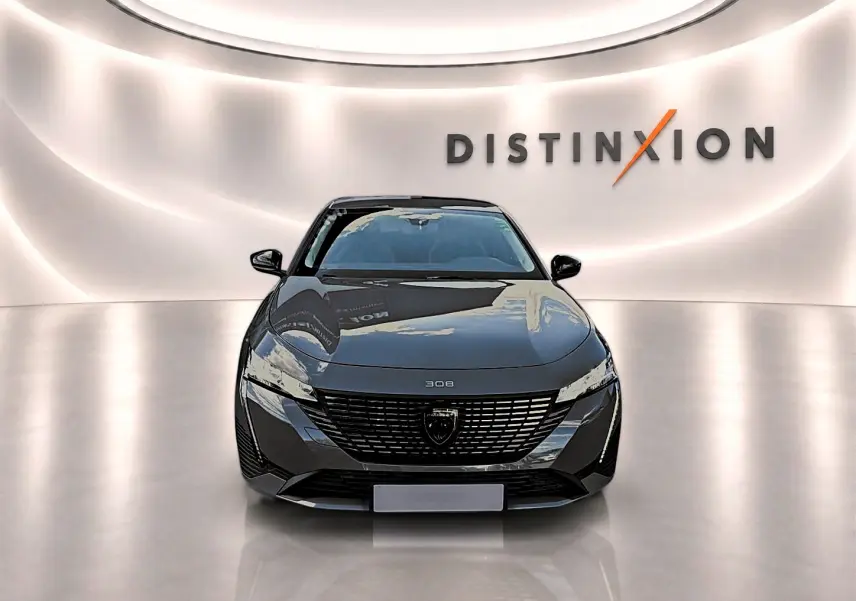 Vue avant d'une Peugeot 308 gris selenium dans un showroom lumineux avec logo Distinxion en arrière-plan.
