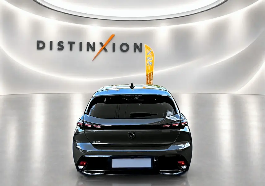 Vue arrière d'une Peugeot 308 gris selenium 2025 avec feux LED et double sortie d'échappement en showroom.