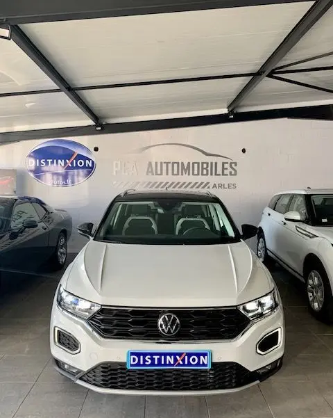 Volkswagen T-Roc blanc vue de face en intérieur, avec calandre noire et phares LED allumés.