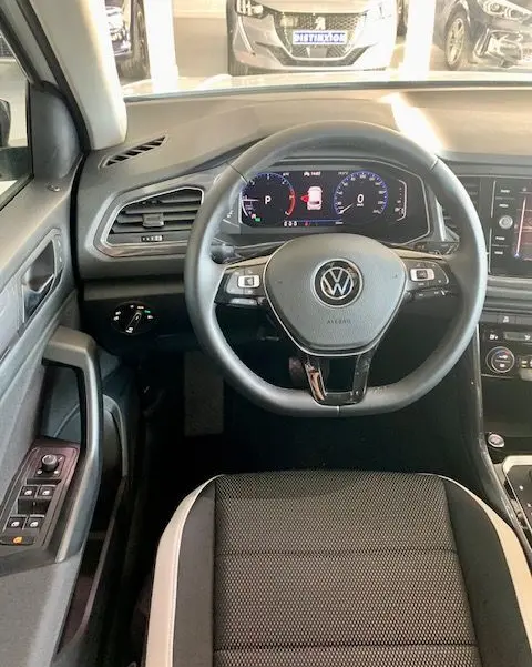 Vue intérieure du Volkswagen T-Roc 2021 montrant le volant cuir noir avec commandes et tableau de bord numérique.