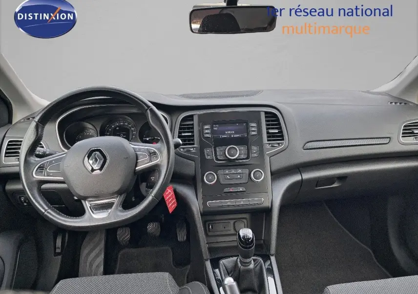 Vue intérieure frontale du tableau de bord et volant noir d’une Renault Mégane IV TCe 100 CH LIFE de 2016 avec boîte manuelle.