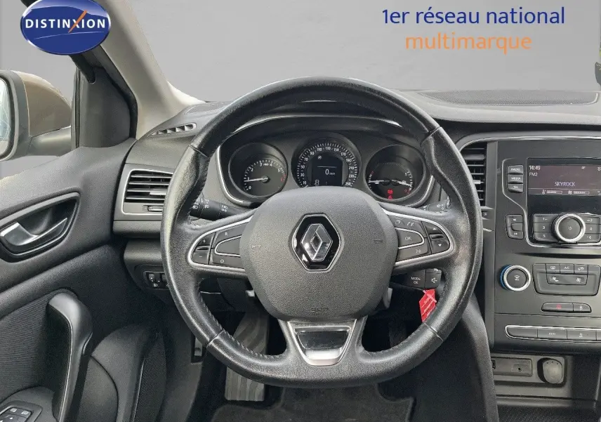 Vue intérieure centrée sur le volant noir d’une Renault Mégane IV brun capuccino, avec tableau de bord et console centrale visibles.