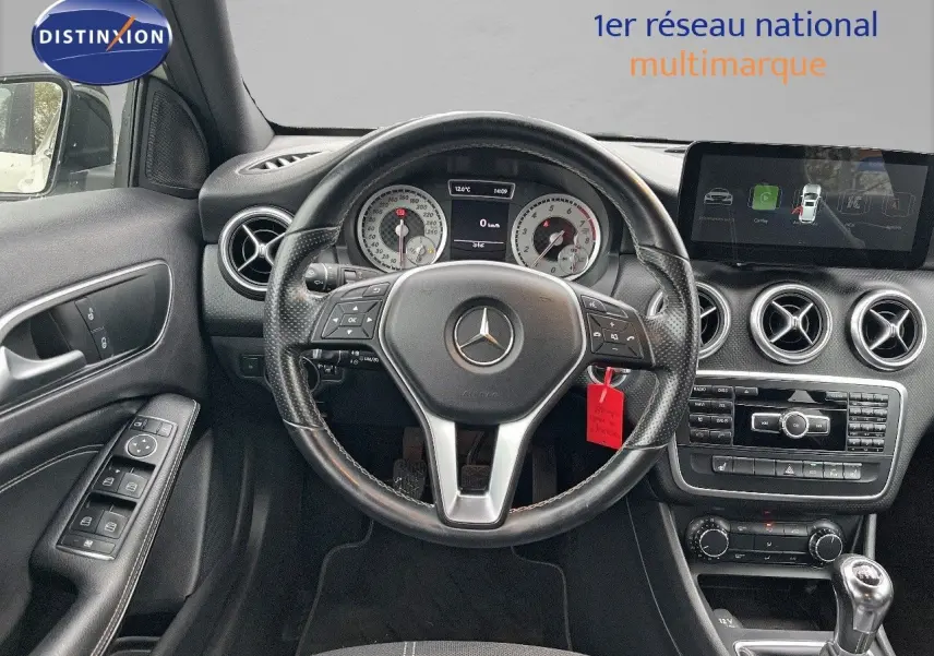 Vue intérieure du poste de conduite d'une Mercedes Classe A 180 Sensation blanche de 2013 avec volant multifonction et boîte manuelle.