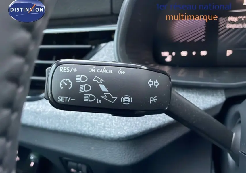 Gros plan sur le commodo de régulateur de vitesse du Skoda Kamiq gris graphite, avec tableau de bord flou en arrière-plan.