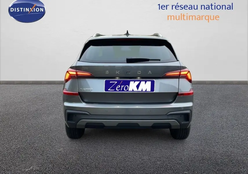 Vue arrière d'un Skoda Kamiq gris graphite métal 2025 avec feux allumés sur fond neutre.
