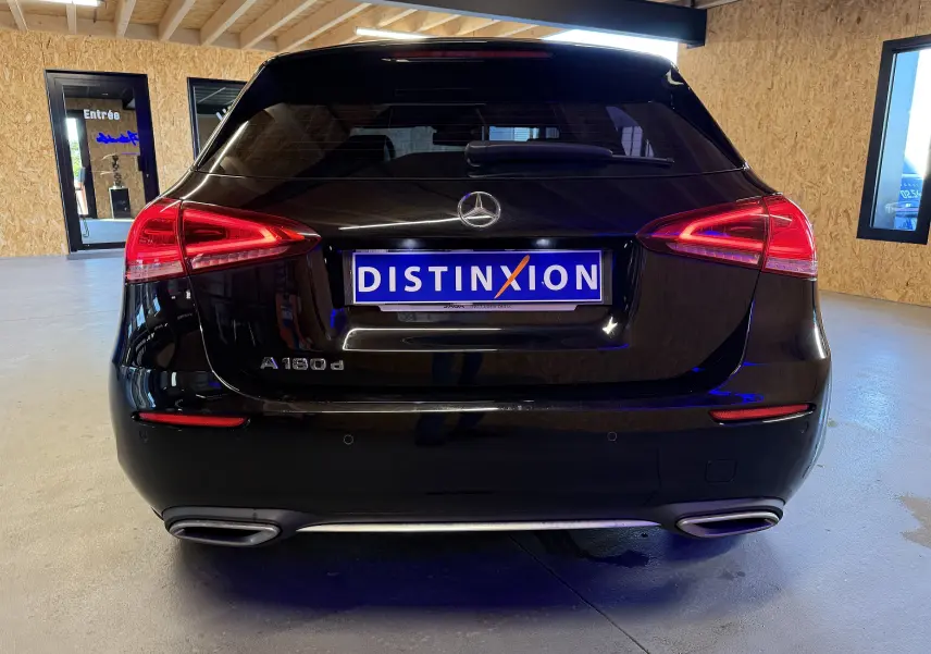 Vue arrière d'une Mercedes Classe A noire avec feux LED et sorties d'échappement chromées dans un garage.