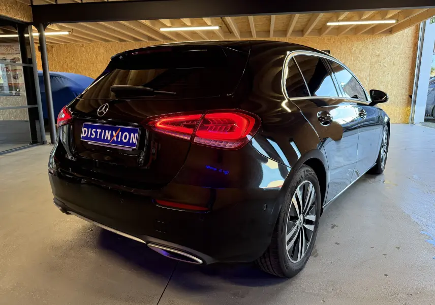 Vue 3/4 arrière droite d'une Mercedes Classe A noire avec feux arrière LED et sorties d'échappement chromées dans un garage.