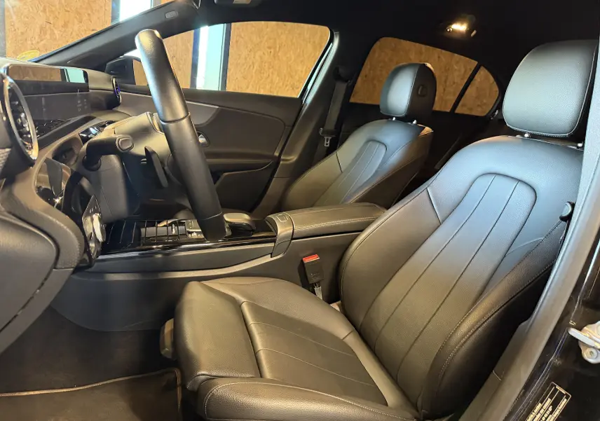 Vue intérieure côté conducteur de la Mercedes Classe A 2022 avec sièges en cuir noir et tableau de bord moderne.