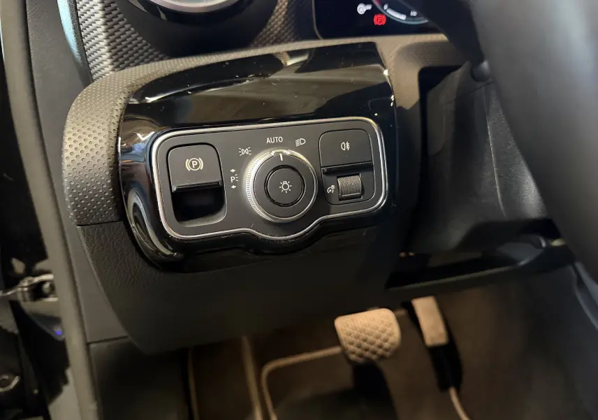 Gros plan sur les commandes d’éclairage noires et brillantes côté gauche du tableau de bord d’une Mercedes Classe A noire 2022.