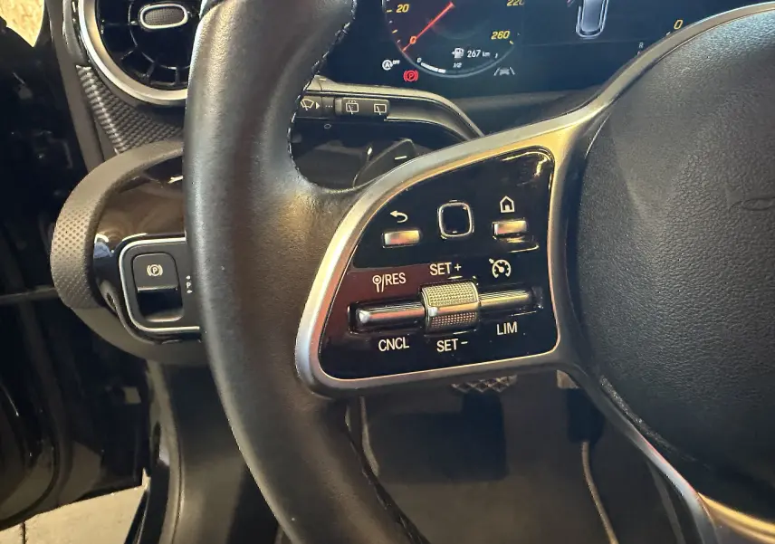 Gros plan sur les commandes multifonctions à gauche du volant cuir noir d'une Mercedes Classe A 2022, tableau de bord numérique visible.