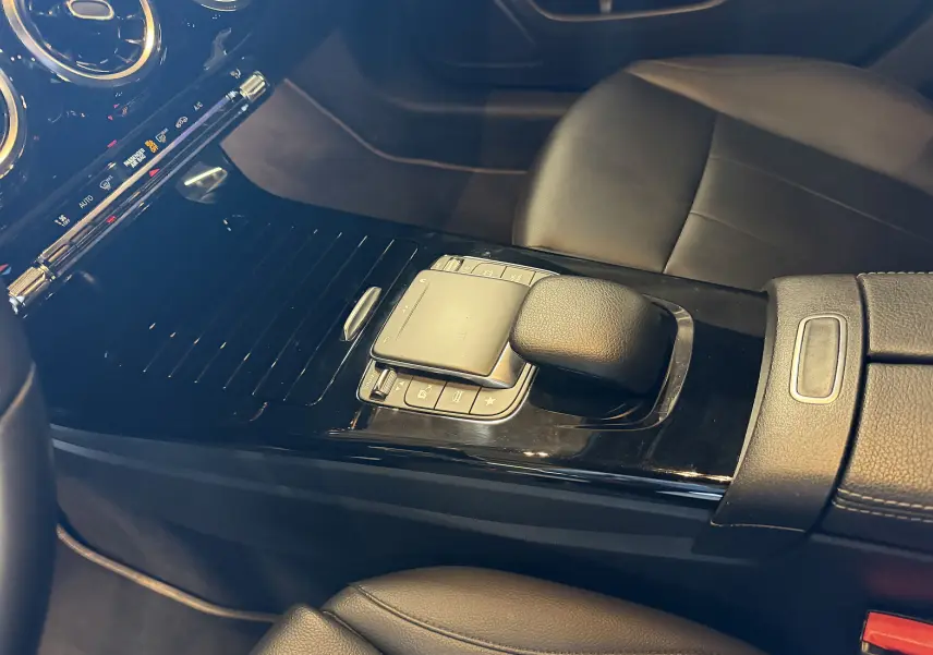 Vue intérieure rapprochée de la console centrale noire de la Mercedes Classe A 2022 avec levier de boîte auto et accoudoir cuir.