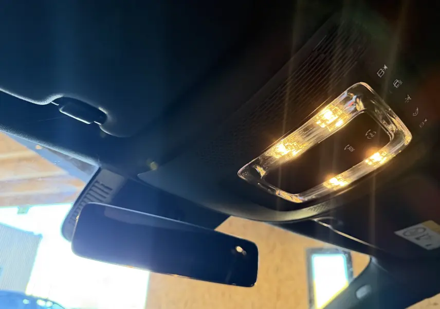 Vue intérieure en plongée du plafonnier allumé et du rétroviseur intérieur d'une Mercedes Classe A noire 2022.