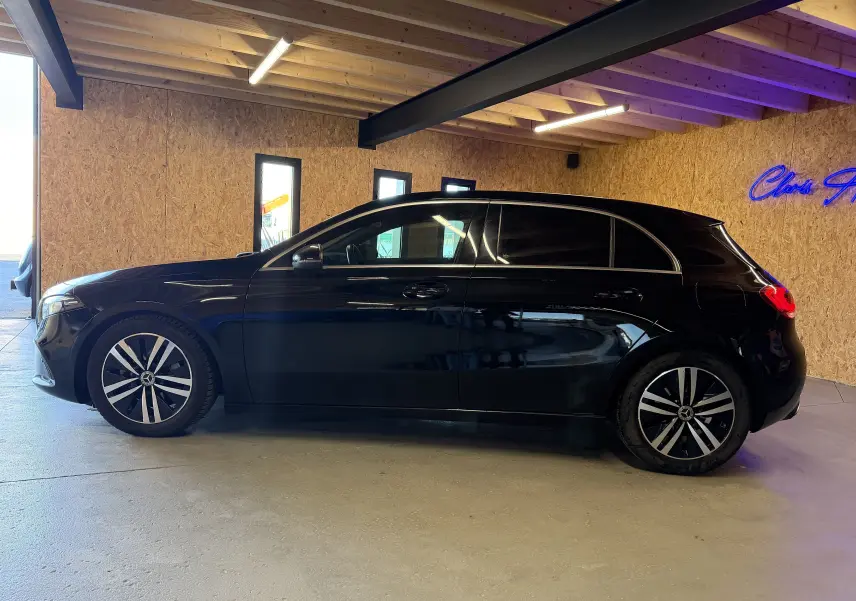 Vue de profil côté gauche d'une Mercedes Classe A noire avec jantes alliage et vitres teintées dans un garage.