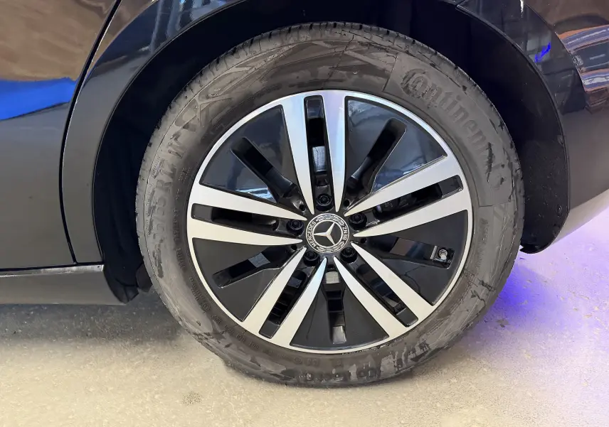 Gros plan sur la jante alu bicolore noir et argent d'une Mercedes Classe A noire, côté arrière droit.