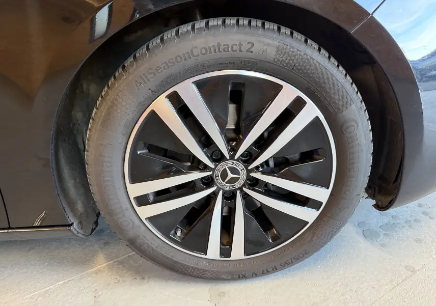 Gros plan sur la jante alu bicolore noire et argentée d'une Mercedes Classe A noire, roue avant côté gauche.