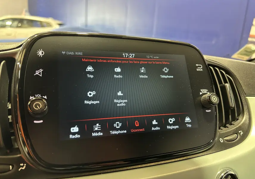 Écran tactile central de la Fiat 500 2023 affichant les options radio, média, téléphone et réglages, intérieur beige.