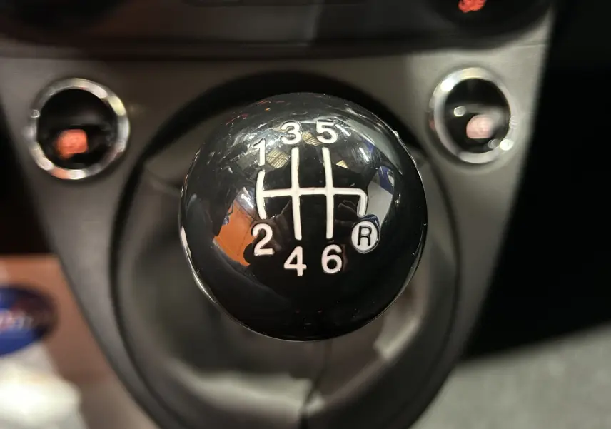 Gros plan sur le levier de vitesses manuel noir de la FIAT 500 70 Hybride Pack Confort & Style 2023.