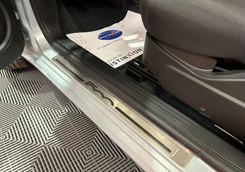 Vue rapprochée de la porte côté gauche d’une Fiat 500 2023 Rugiada Green avec seuil de porte métallique marqué 500.