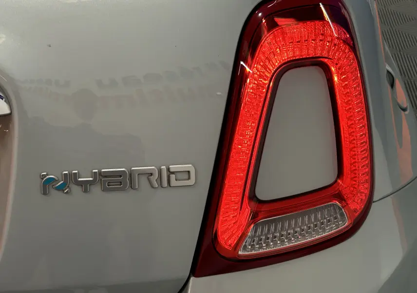 Gros plan sur le feu arrière droit rouge et le badge HYBRID d'une FIAT 500 Rugiada Green 2023.