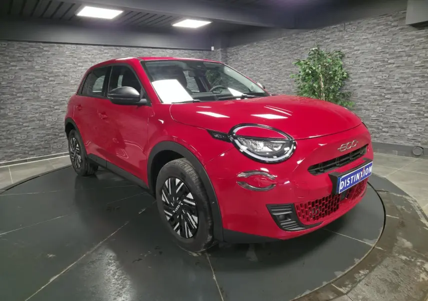 Vue 3/4 avant droite d'une FIAT 600 rouge 2024 avec jantes acier bicolores et coques de rétroviseurs noires.