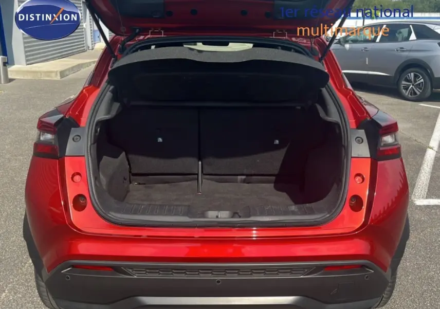 Vue arrière avec coffre ouvert du Nissan Juke 2024 rouge Fuji Metal, soulignant son espace de chargement généreux.