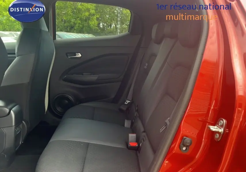 Vue intérieure côté arrière droit du Nissan Juke rouge Fuji Metal 2024, montrant les sièges arrière en tissu noir.
