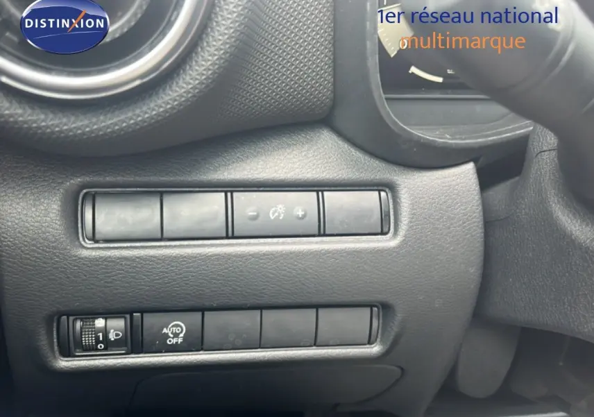 Détail intérieur montrant les commandes de réglage d’éclairage et tableau de bord en plastique noir texturé.