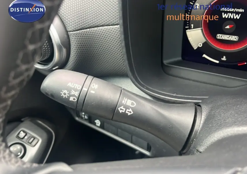 Gros plan sur la commande des feux et clignotants du Nissan Juke 2024, intérieur noir, détails fonctionnels visibles.
