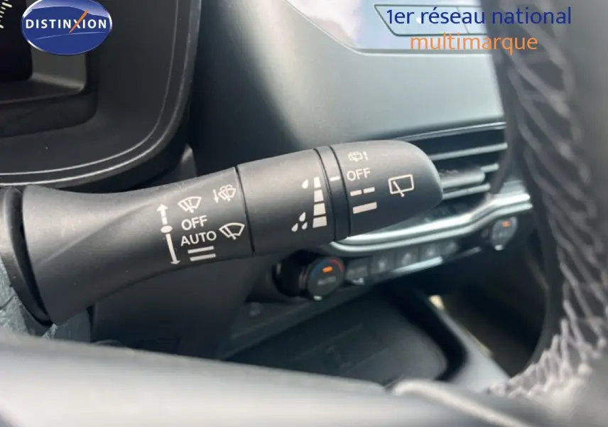 Gros plan sur la commande d’essuie-glace à gauche du volant dans l’habitacle du Nissan Juke rouge Fuji Metal 2024.