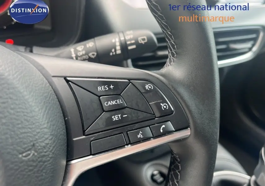 Gros plan sur les commandes de régulateur de vitesse au volant noir du Nissan Juke 2024 rouge Fuji Metal.