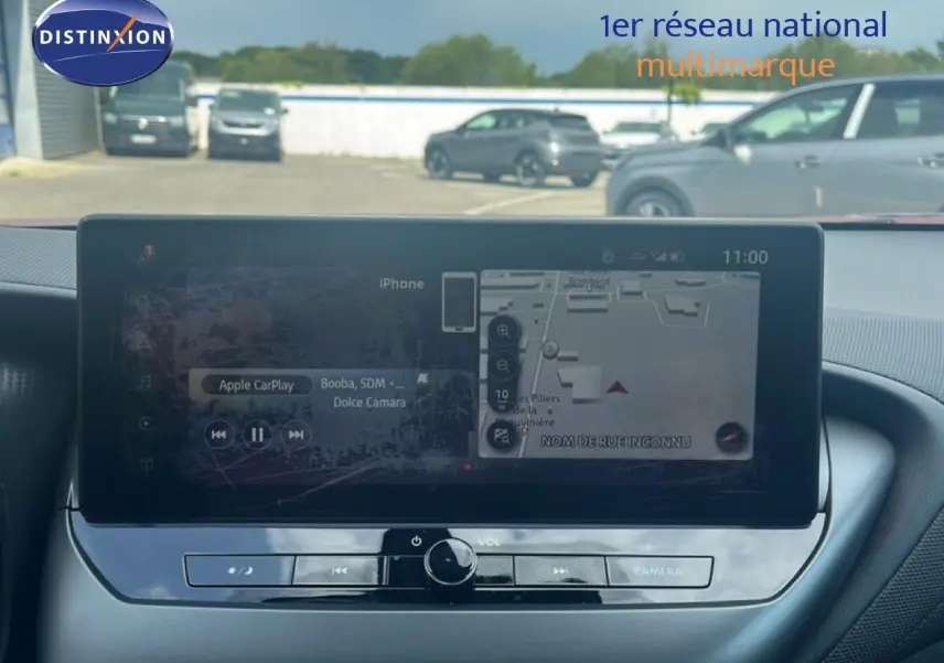 Vue intérieure centrée sur l’écran tactile du tableau de bord du Nissan Juke rouge Fuji Metal 2024, affichant la navigation.