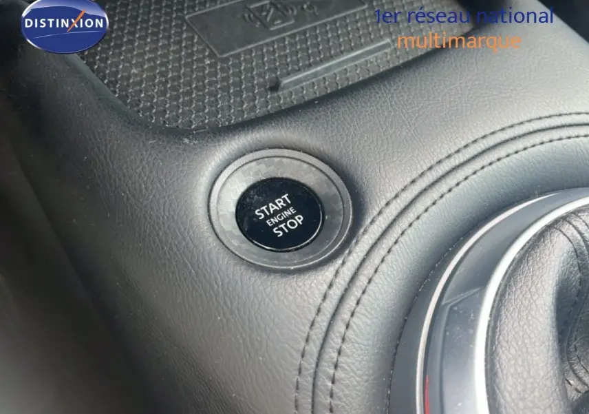Détail intérieur montrant le bouton Start/Stop et la console en cuir noir du Nissan Juke rouge Fuji Metal 2024.