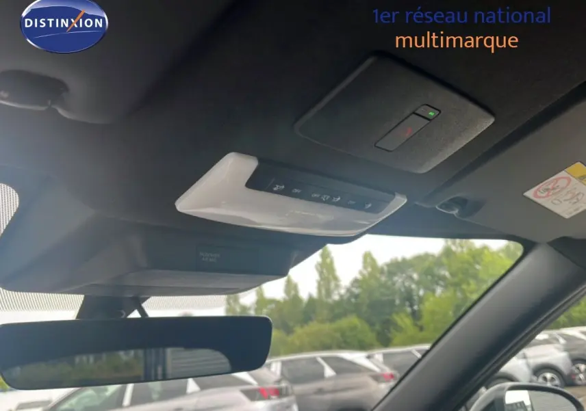 Vue intérieure du toit et rétroviseur d’un Nissan Juke rouge Fuji Metal 2024, avec commandes intégrées au plafond.