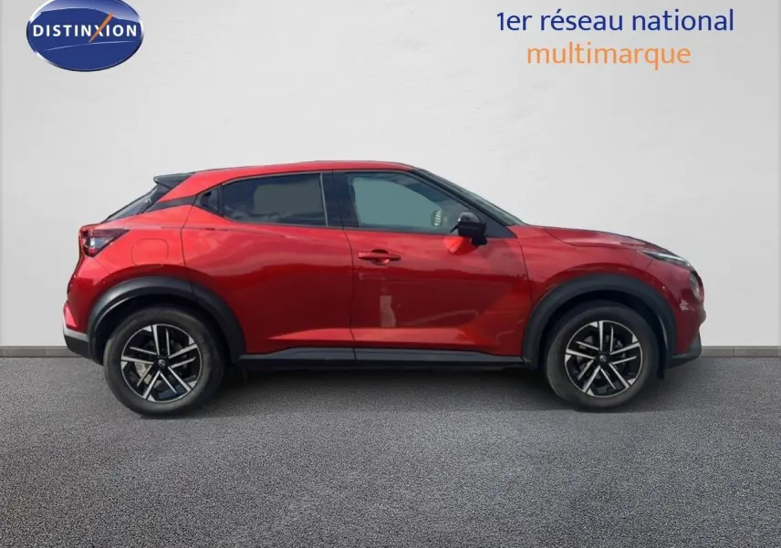 Profil côté gauche d'un Nissan Juke 2024 rouge Fuji Metal avec jantes alliage noires et toit noir.