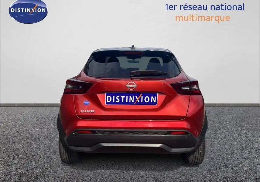 Vue arrière d'un Nissan Juke 2024 rouge Fuji Metal avec toit noir et feux arrière LED distinctifs.