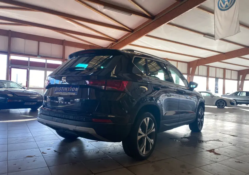 Vue 3/4 arrière droite d'un SEAT Ateca noir 2019 dans un showroom lumineux avec jantes alliage et toit ouvrant.
