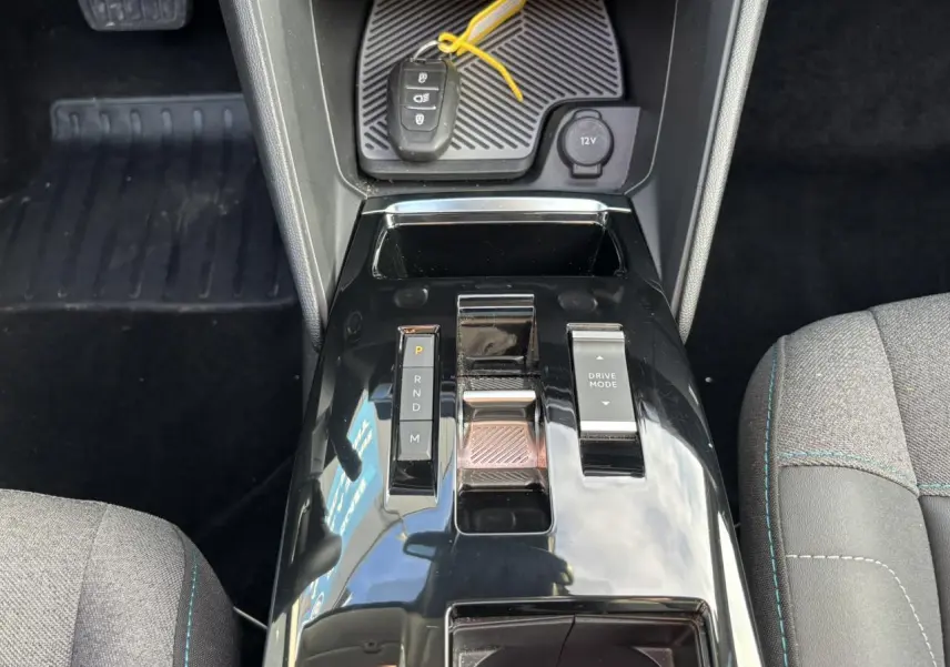 Vue plongeante sur la console centrale noire brillante de la Citroën C4 2024 avec levier de vitesses et bouton Drive Mode.