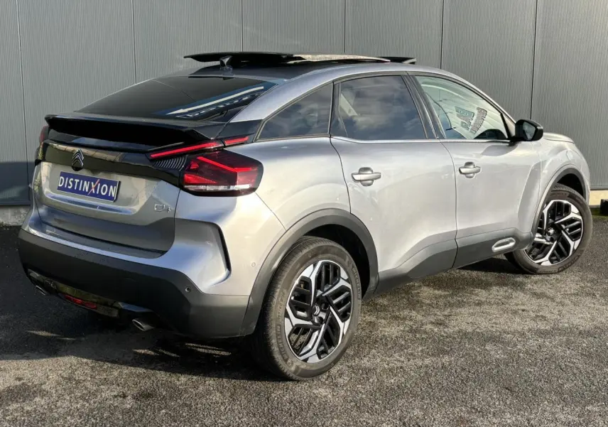 Vue 3/4 arrière droite d'une Citroën C4 gris Artense avec toit ouvrant noir et jantes alliage 18 pouces.