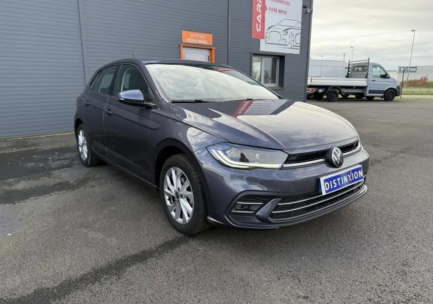 Volkswagen Polo gris cendre vue 3/4 avant droit, avec jantes alliage et feux LED allumés.